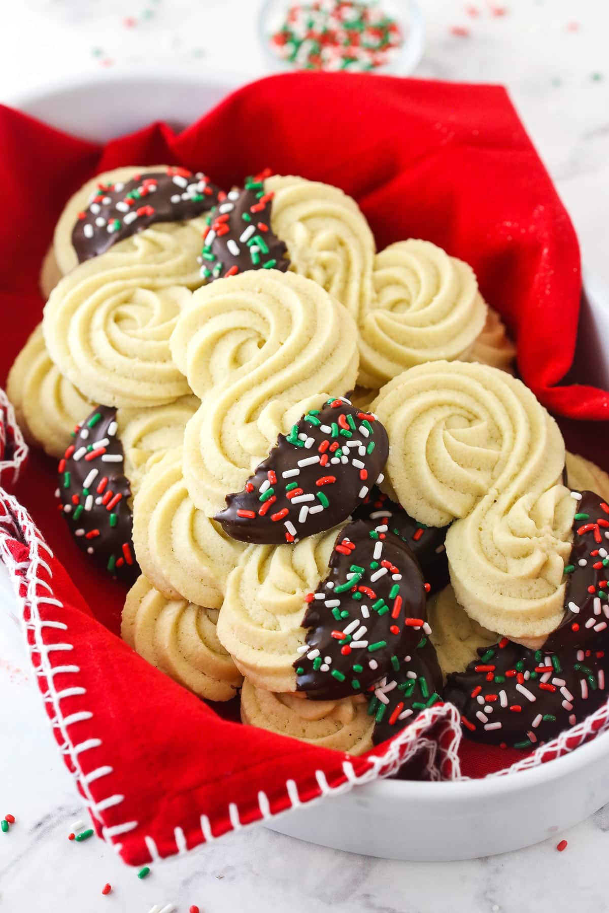 German Spritz Cookies in a white bowl with a decorative red cloth