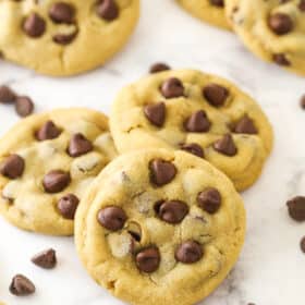 Peanut butter chocolate chip cookies on a counter with chocolate chips sprinkled around