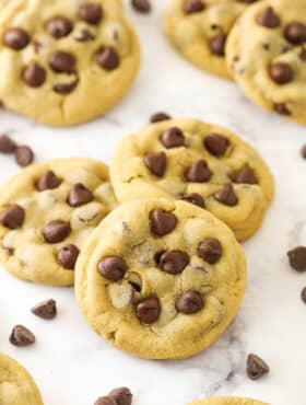 Peanut butter chocolate chip cookies on a counter with chocolate chips sprinkled around