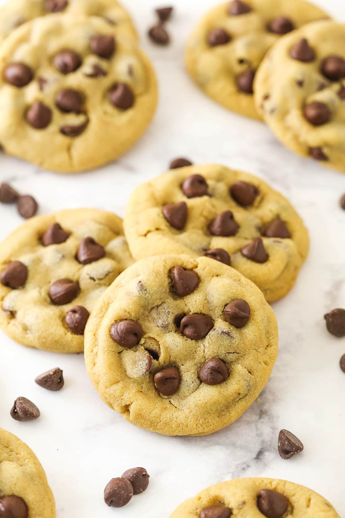 Peanut butter chocolate chip cookies on a counter with chocolate chips sprinkled around