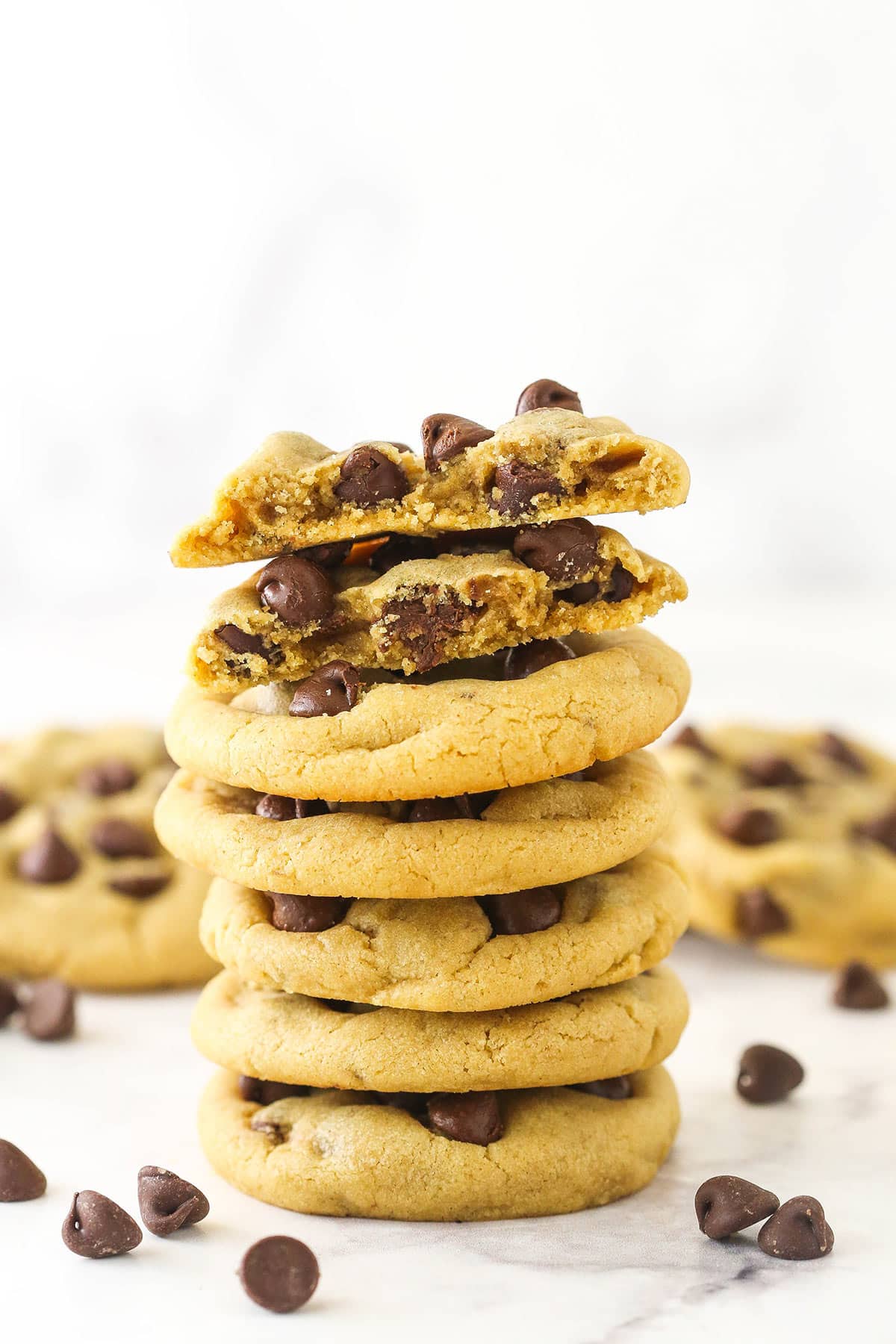 A stack of peanut butter chocolate chip cookies with the top cookie broken in half