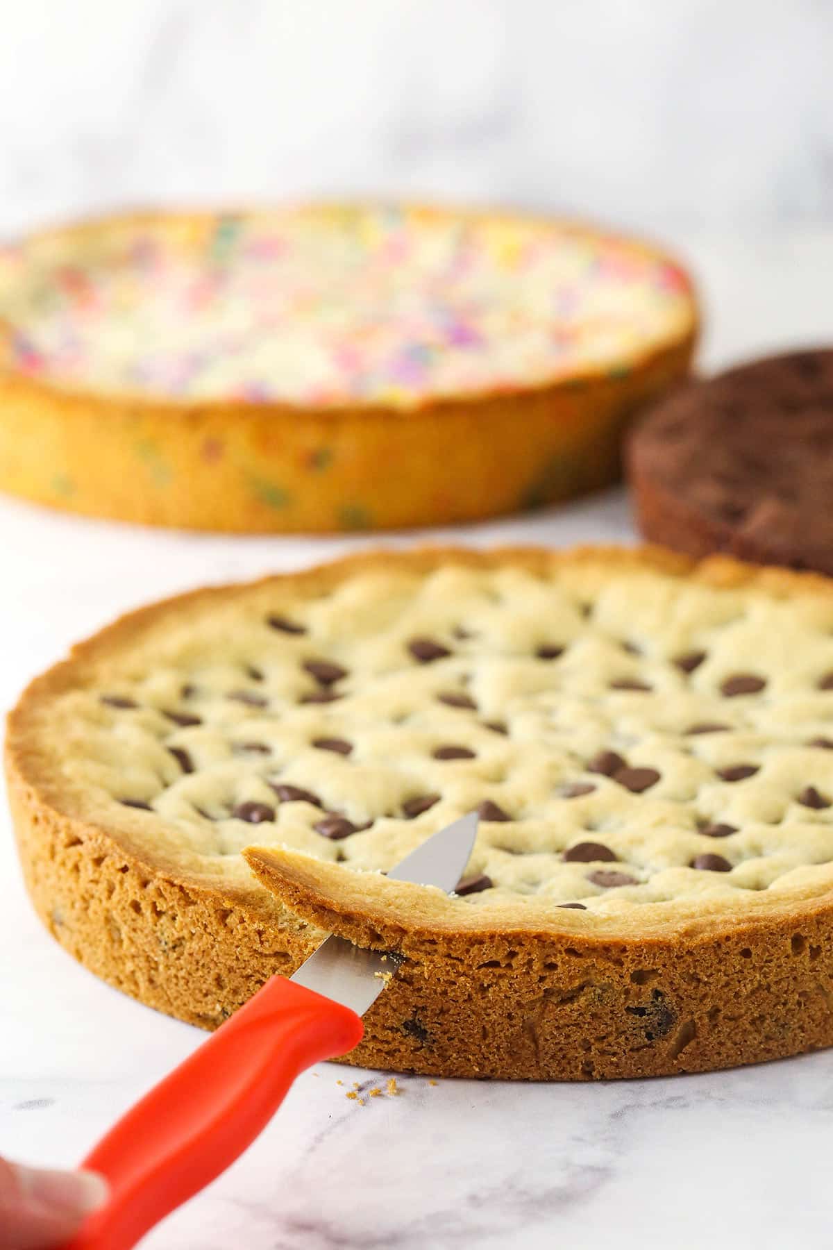 image showing a small knife trimming the edges off of the classic chocolate chip cookie layer