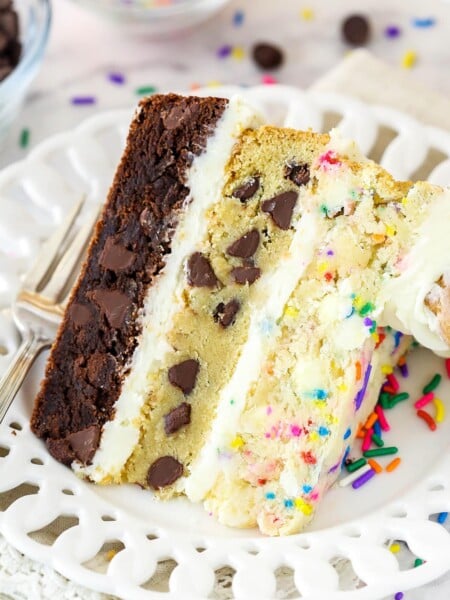slice of ultimate layered cookie cake on a white plate