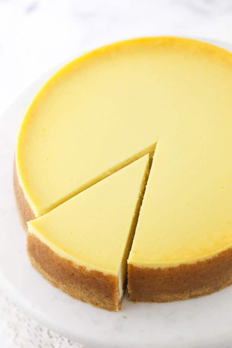 a full vanilla cheesecake with a slice cut and slightly removed