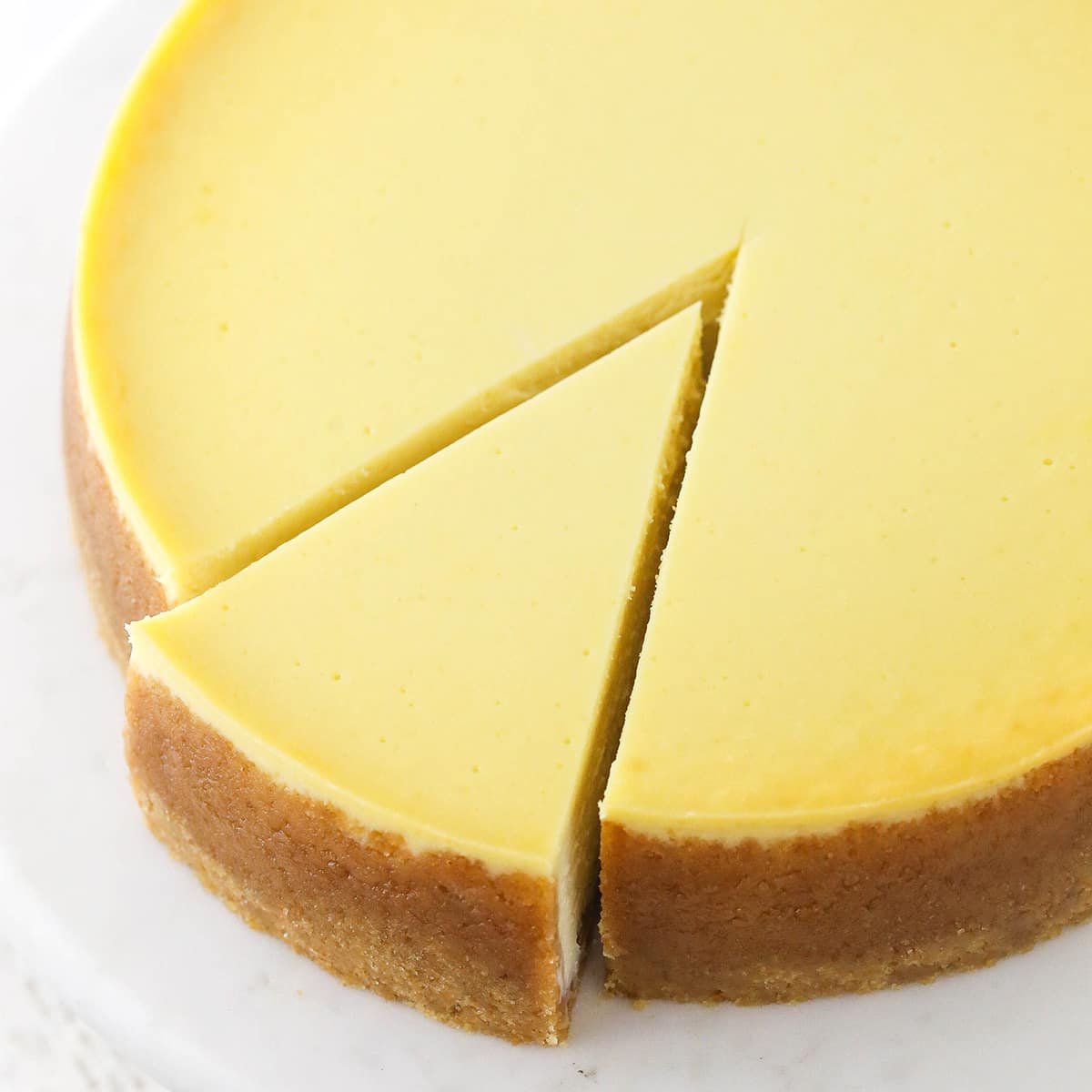 a full vanilla cheesecake with a slice cut and slightly removed