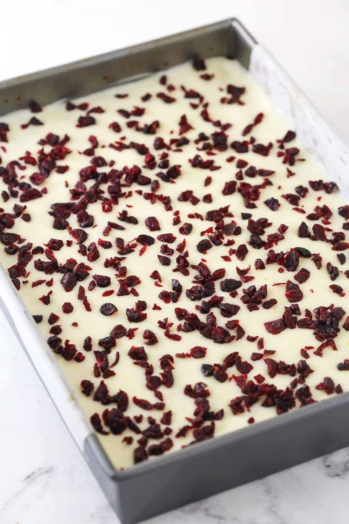 Adding cranberries to the frosted blondies.