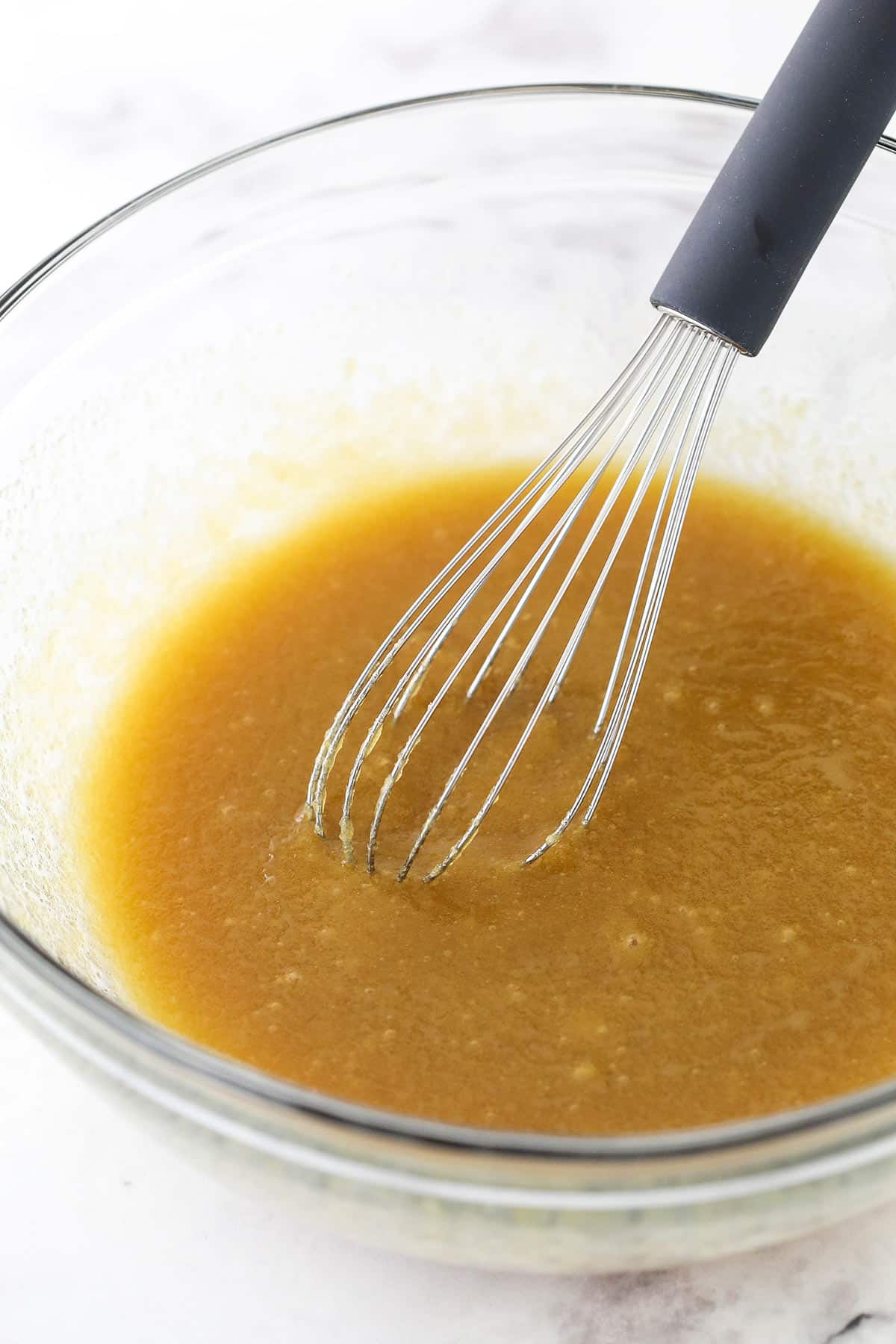 Mixing melted butter and sugar in a glass bowl