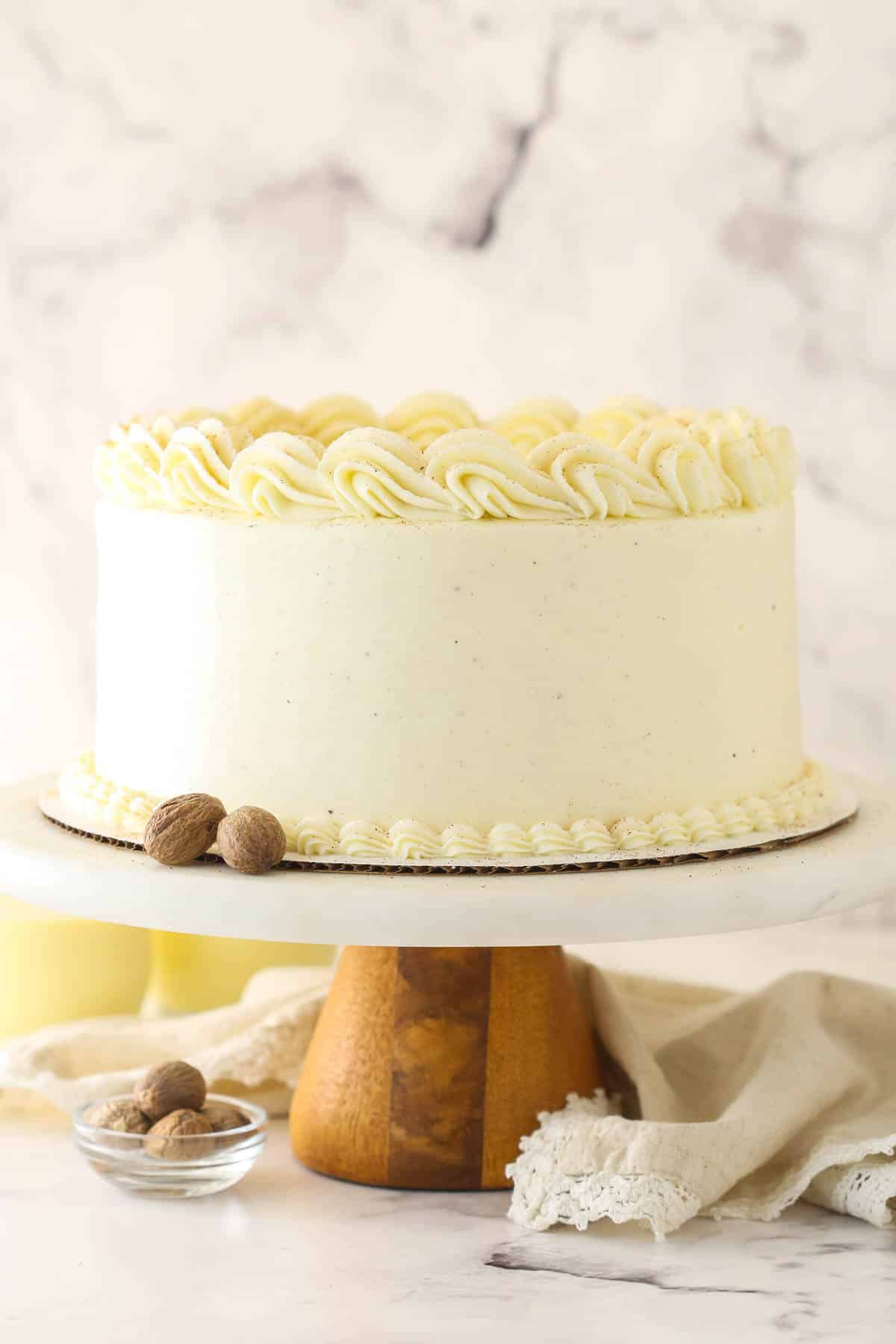 Frosted eggnog layer cake on a wooden cake stand