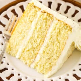 A slice of frosted eggnog layer cake on a white plate.