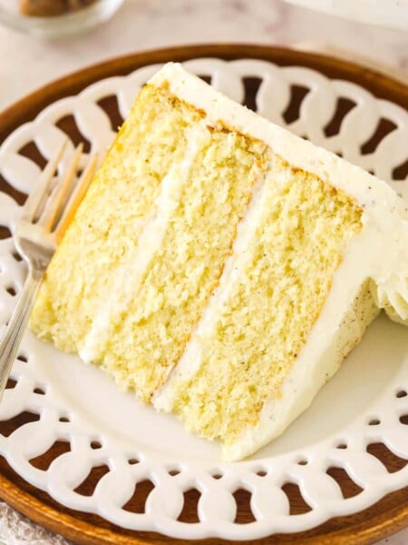 A slice of frosted eggnog layer cake on a white plate.