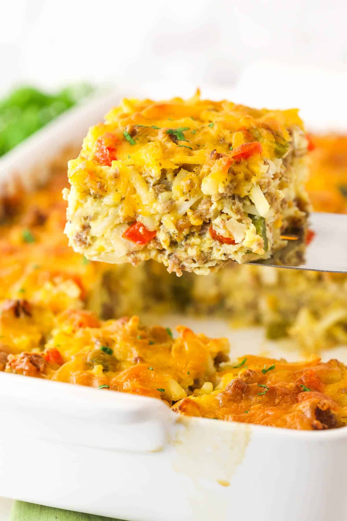 A piece of hashbrown breakfast casserole being lifted out of the baking dish