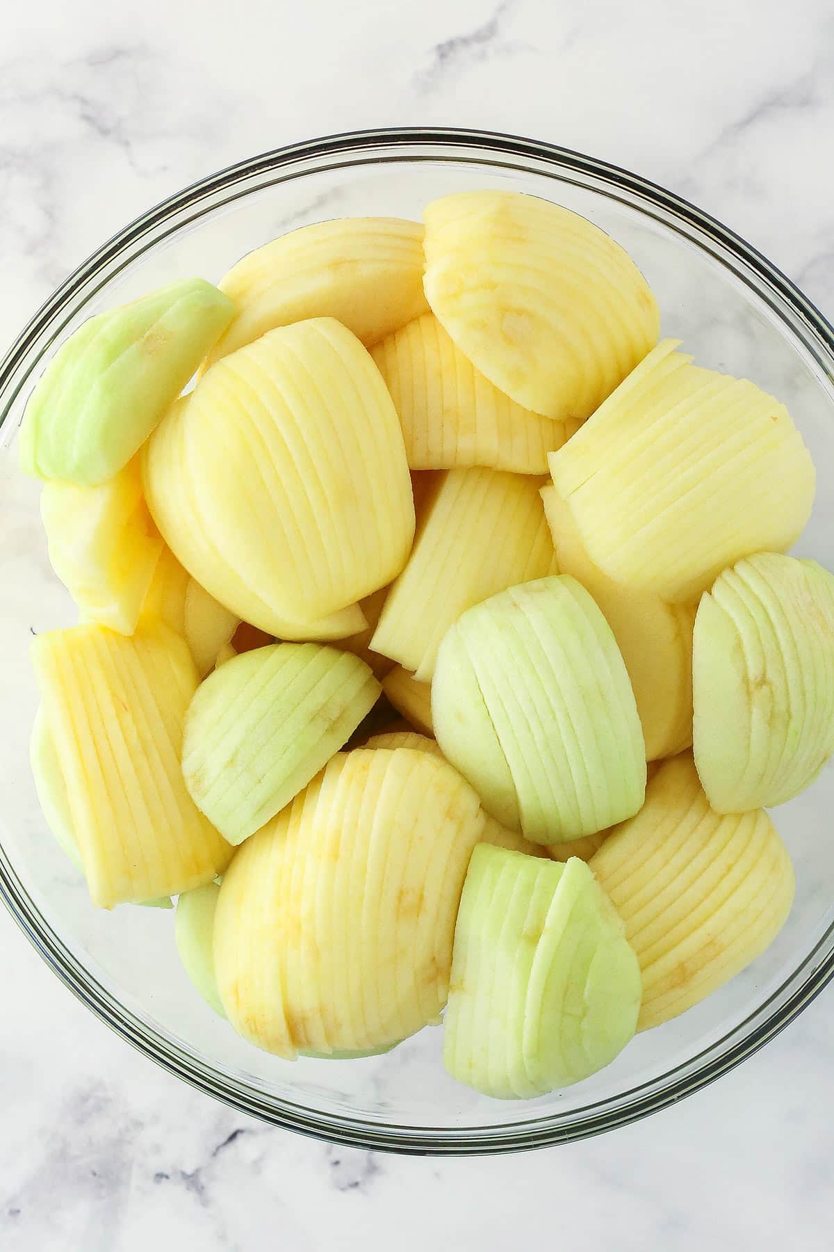 Thinly sliced apples in a glass bowl.