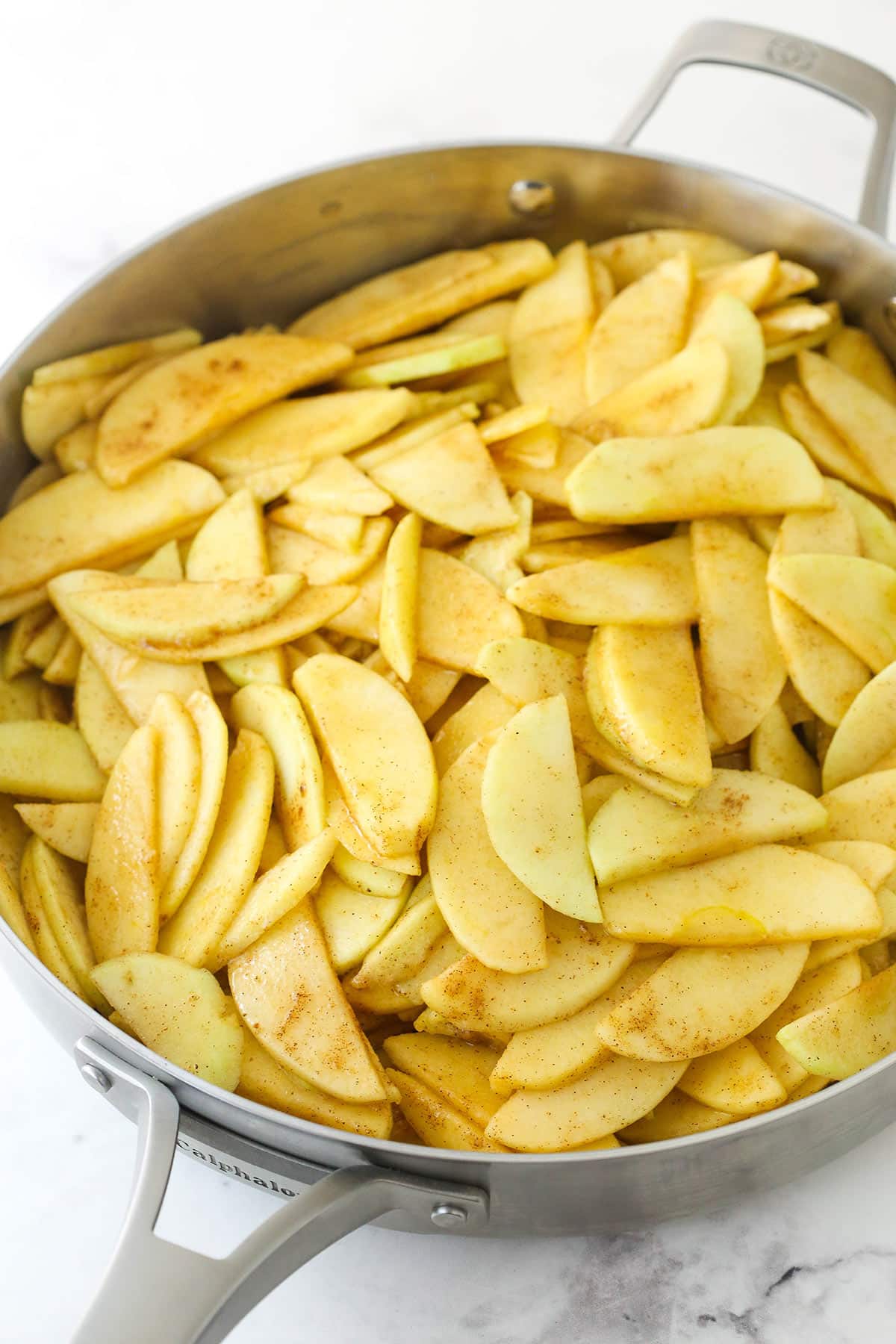 Cooking apple slices in a metal pan.