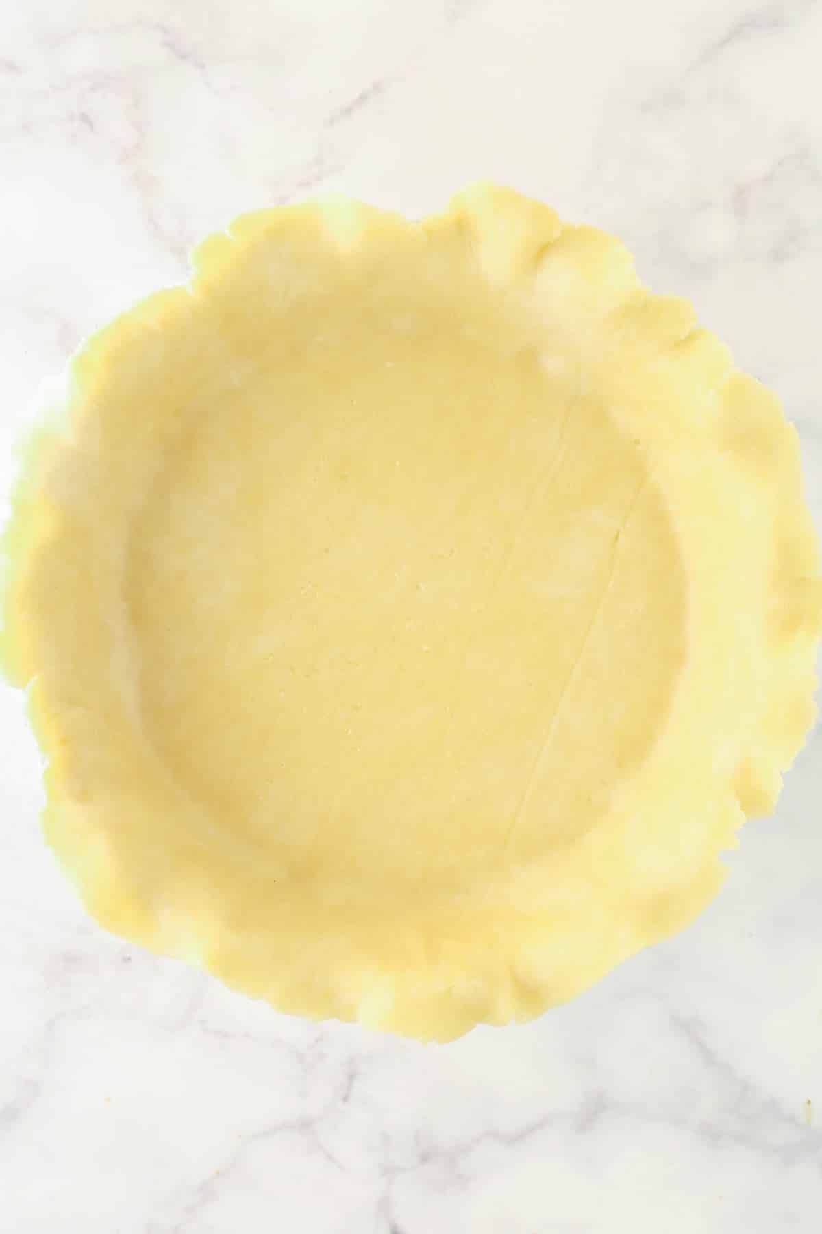 Pie crust dough fitted to a pie pan.