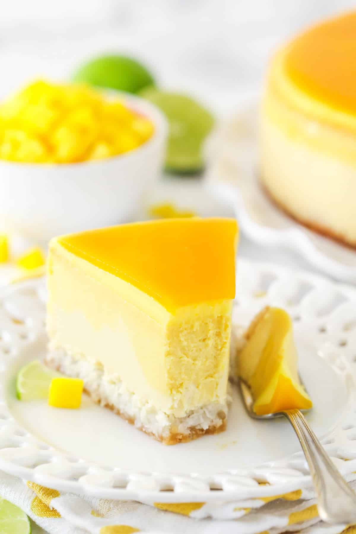 slice of mango key lime cheesecake on white plate white a bite taken