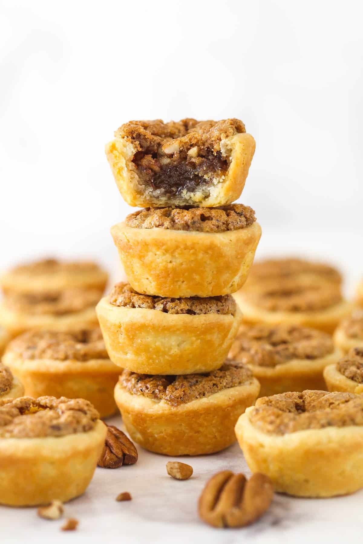 A stack of 4 pecan tassies with a bite missing from the top one