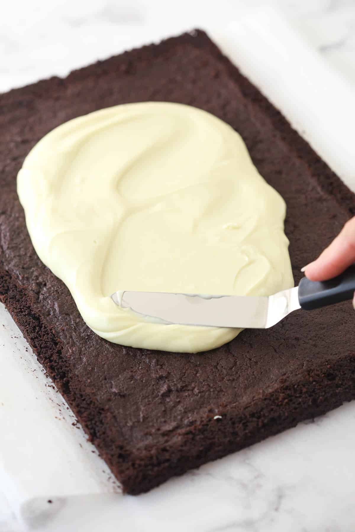 Spreading the white chocolate peppermint topping over the cookie layer.