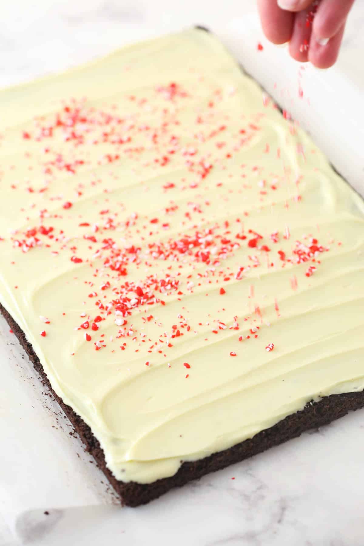 Sprinkling crushed candy canes over the white chocolate layer.