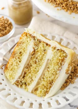 slice of toffee layer cake on white plate with toffee sauce in the background