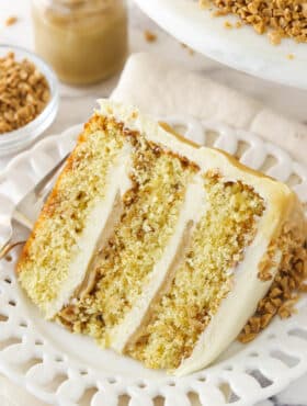 slice of toffee layer cake on white plate with toffee sauce in the background