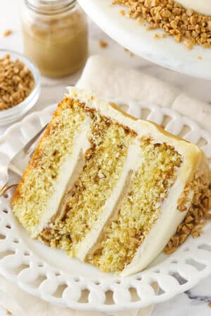 slice of toffee layer cake on white plate with toffee sauce in the background