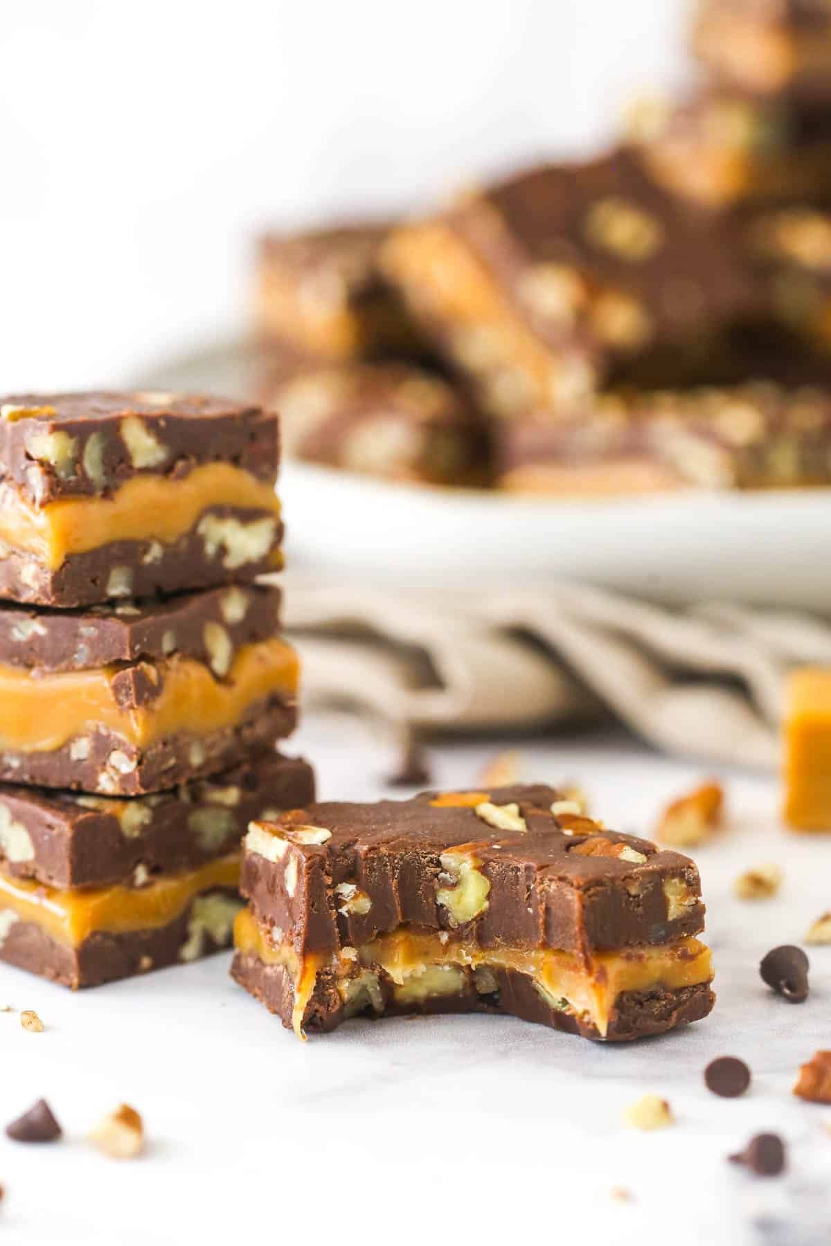 This Turtle Fudge is super delicious, super sweet, and super easy. Rich chocolate, pecans, and creamy caramel combine for a perfect bite!. A piece of turtle fudge with a big bite missing