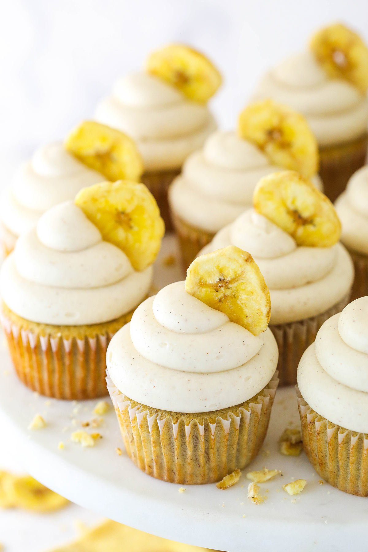 Banana cupcakes with cinnamon cream cheese frosting and a banana chip.