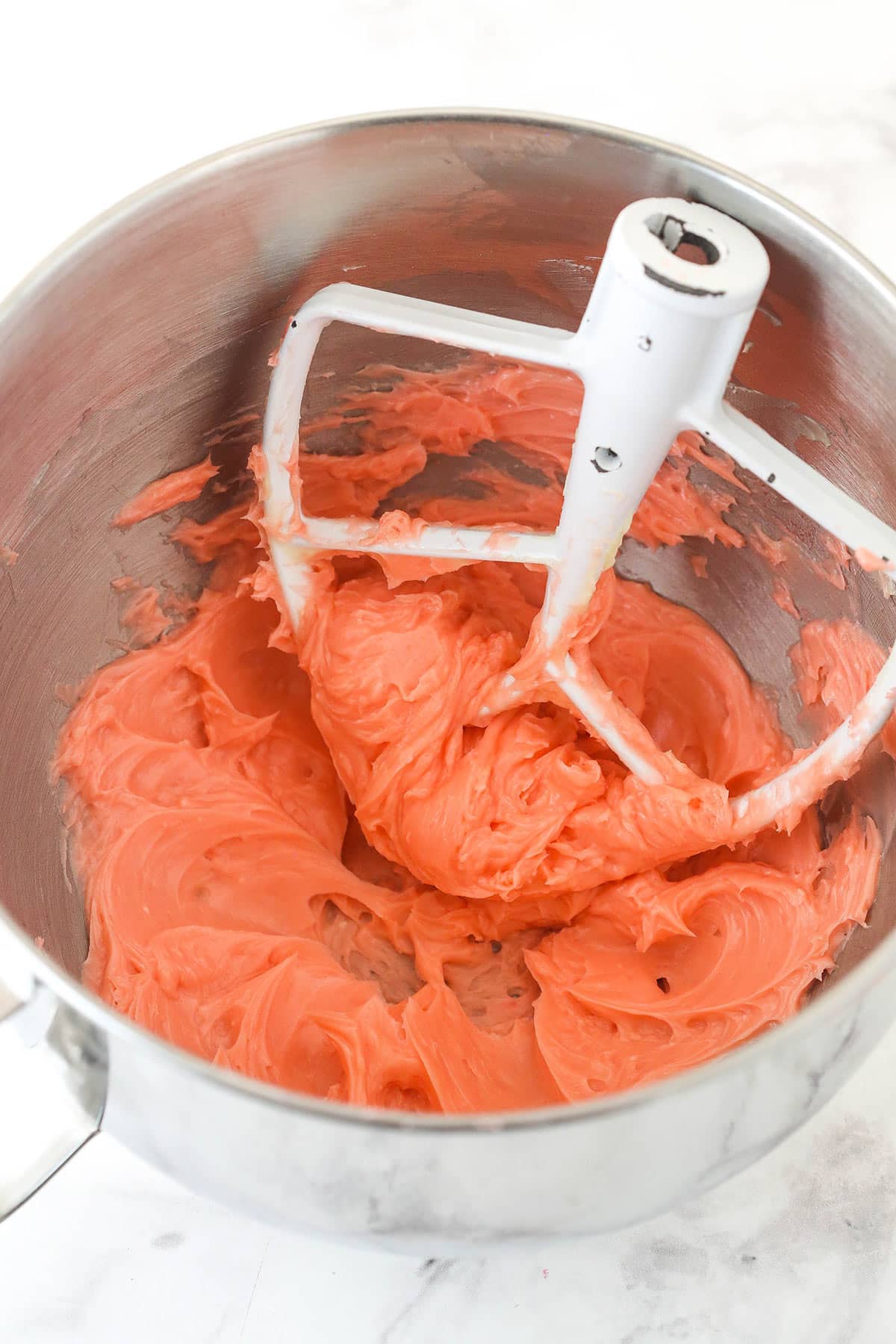 Adding the red food coloring to the creamed butter and sugar.