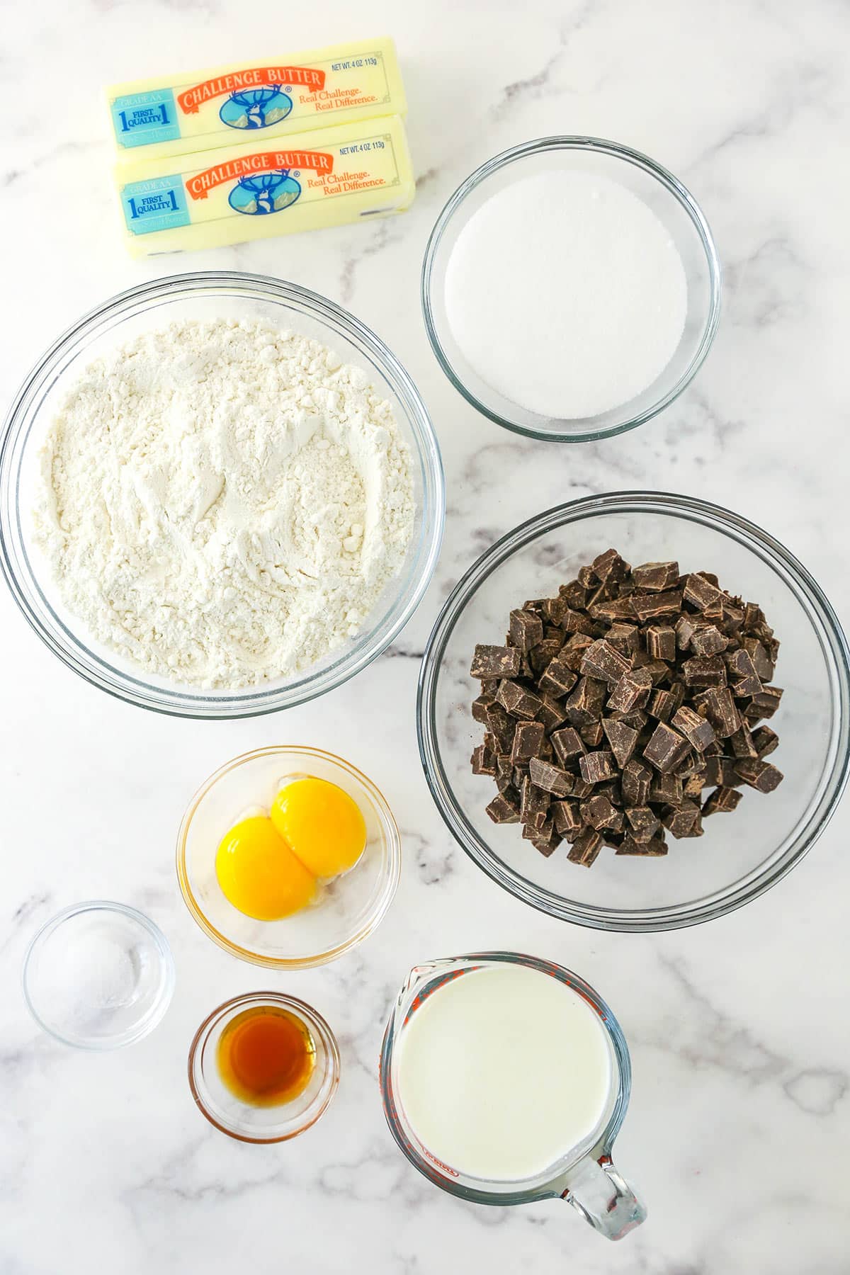 cookie ingredients in glass bowls on marble countertop