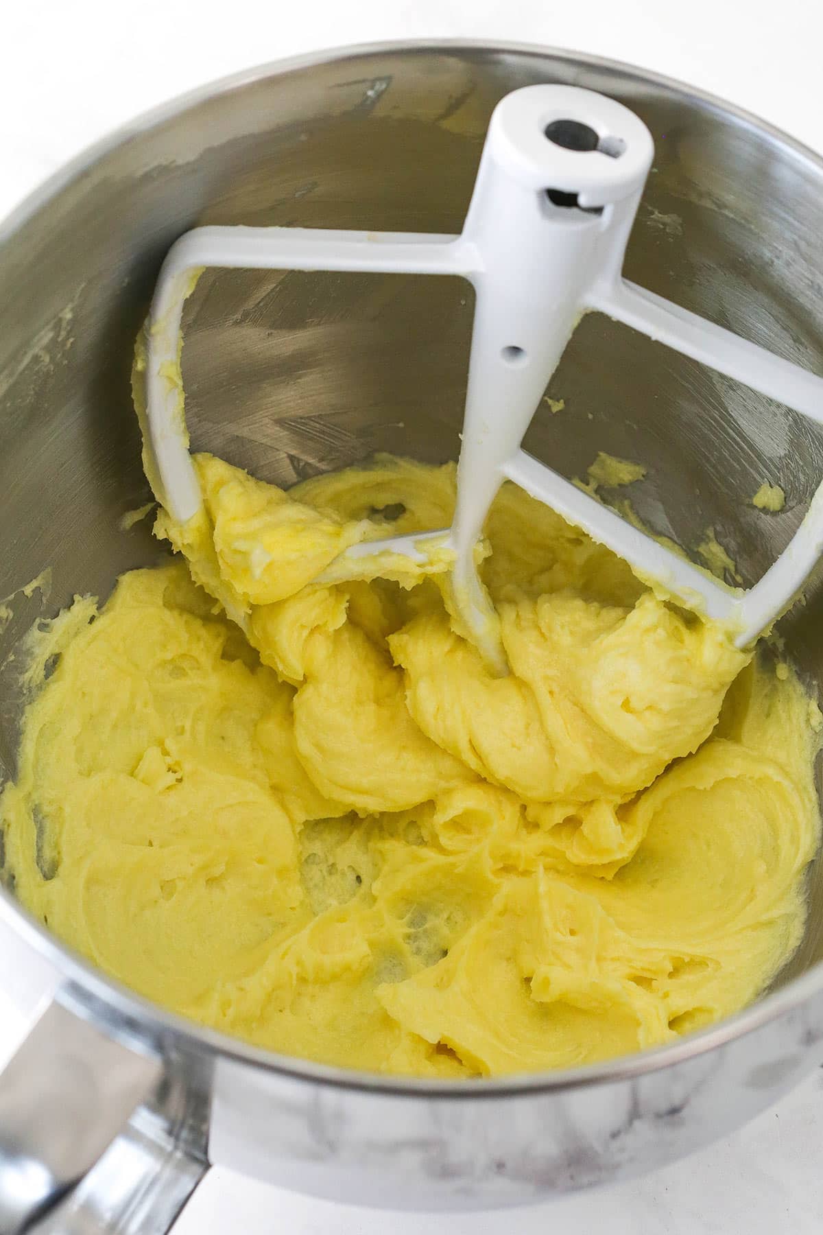 Cookie dough in a mixer bowl after adding the egg yolks and vanilla extract.