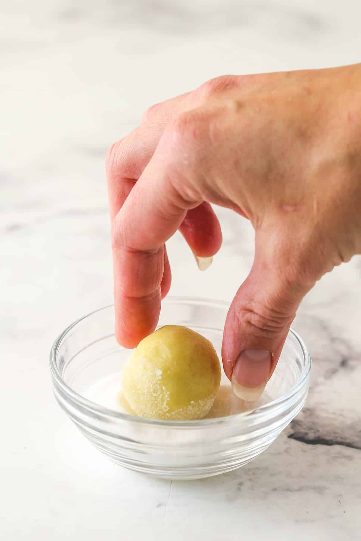Rolling a ball of cookie dough in sugar.