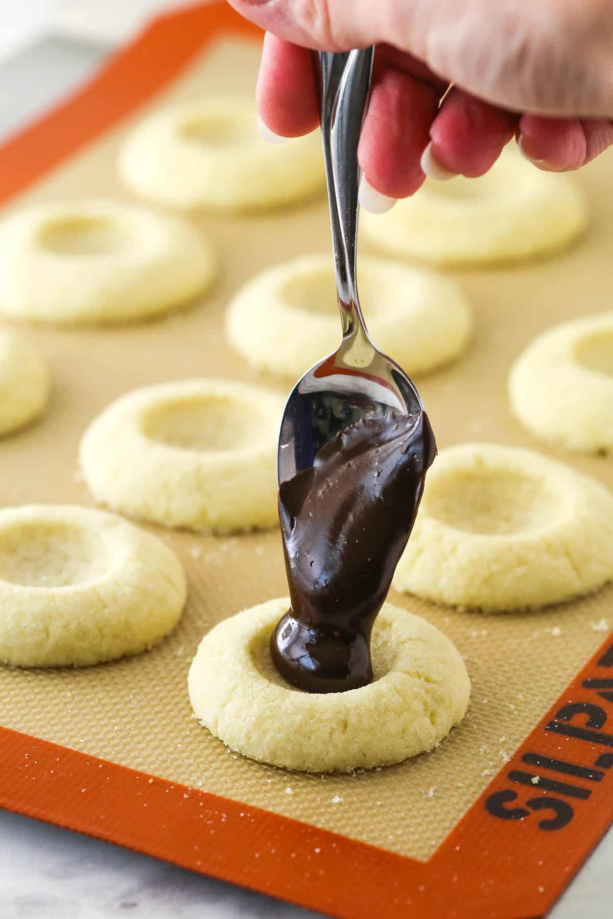 Adding chocolate ganache to the center of a baked cookie.