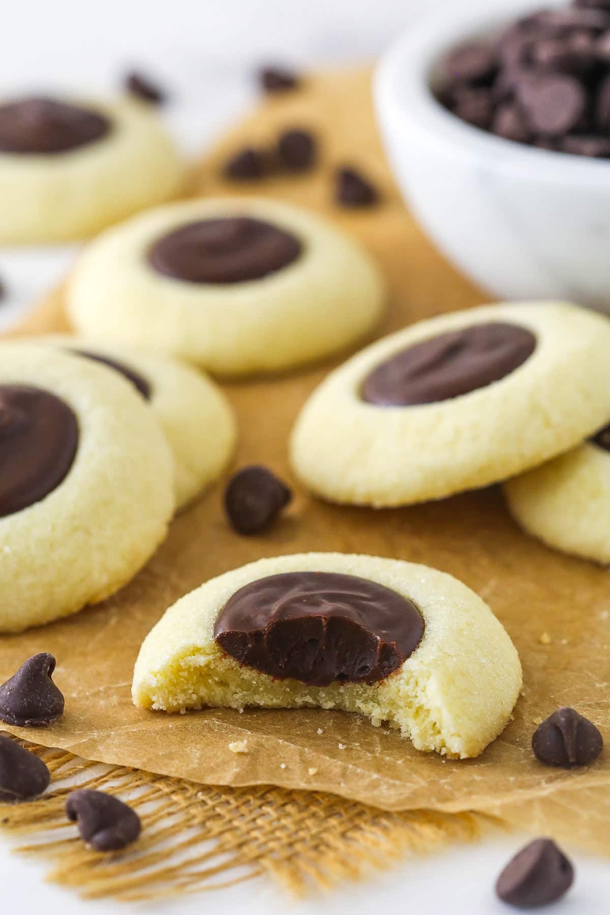 chocolate thumbprint cookies on brown parchment paper with a bite taken out of one