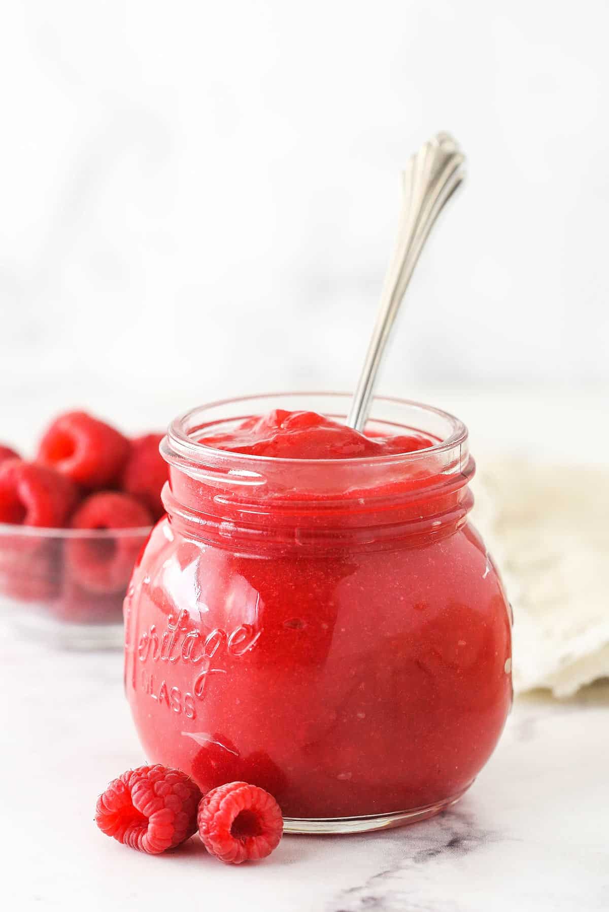 Raspberry filling for cake in a jar with a spoon.