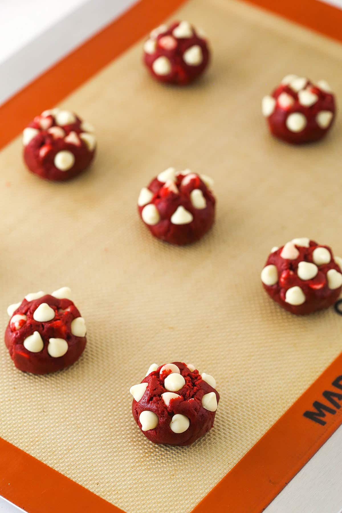 Rolling the dough into balls and placing white chocolate chips on top.