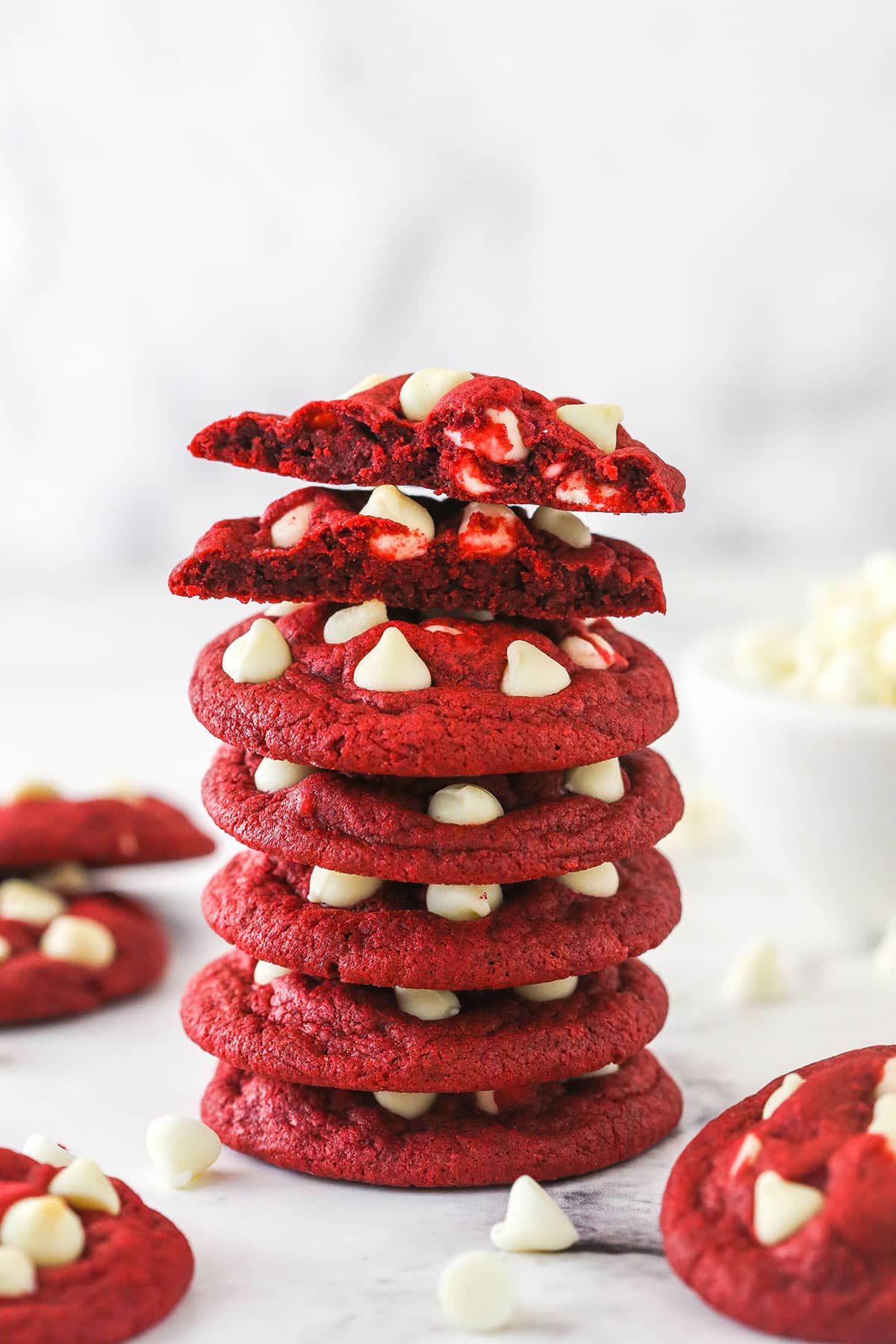 These sweet and creamy red velvet cookies with white chocolate chips are an irresistible treat for your cookie boxes this holiday season. Stack of lots of red velvet cookies with white chocolate chips.