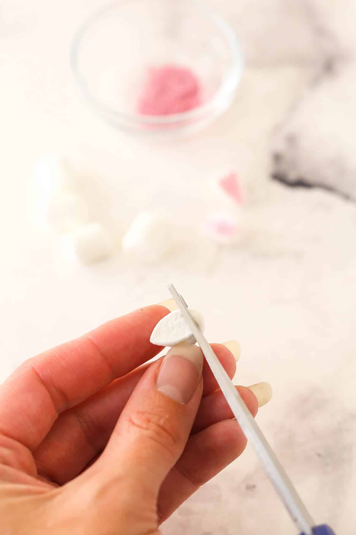 Cutting off one of the pointed ends from the marshmallow halves.