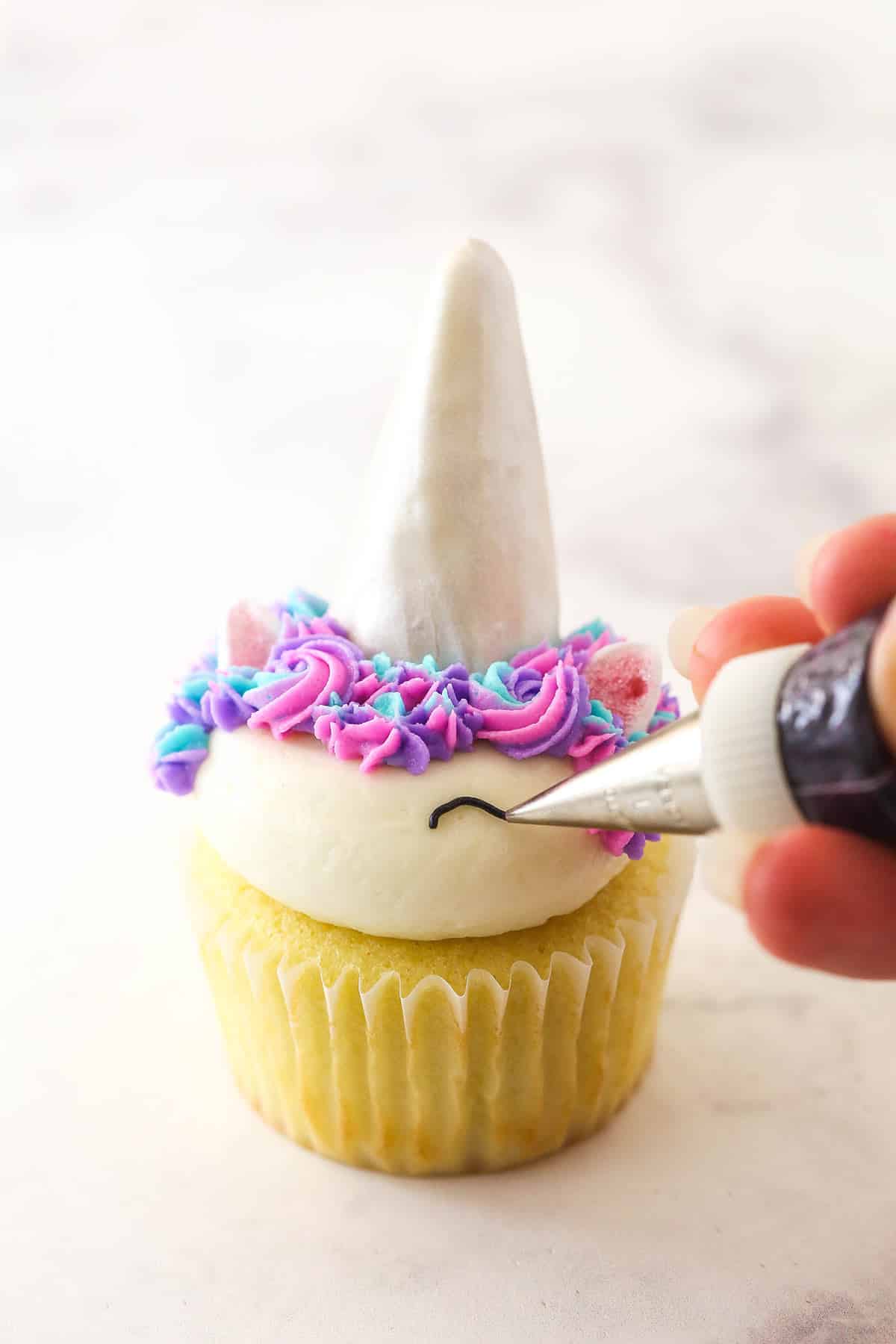 Piping the eyes onto the easy unicorn cupcakes.