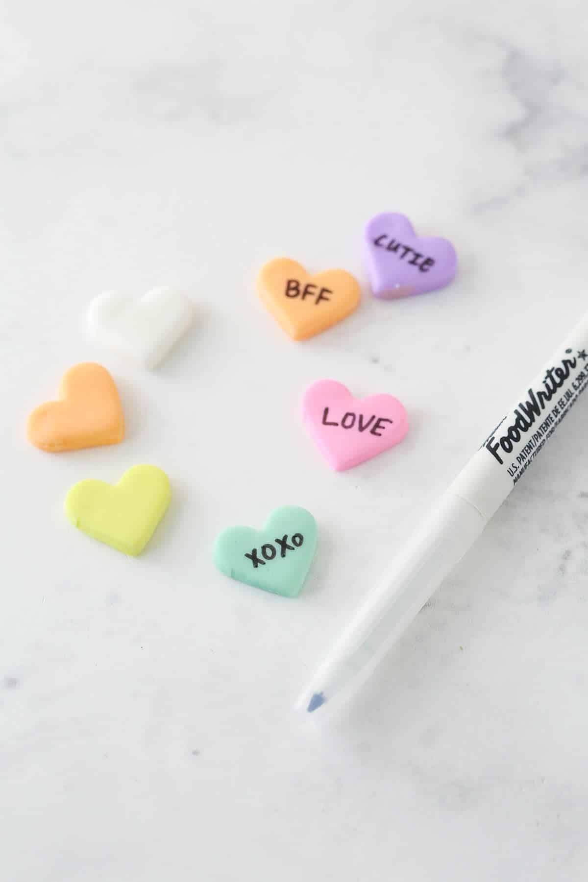 Writing love messages on fondant hearts to top conversation heart cupcakes.