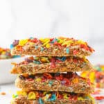 A stack of Fruity Pebbles cookies near a bowl of Fruity Pebbles.