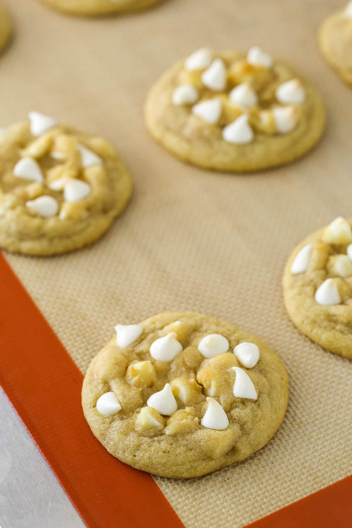 White chocolate chip cookies on a baking mat.