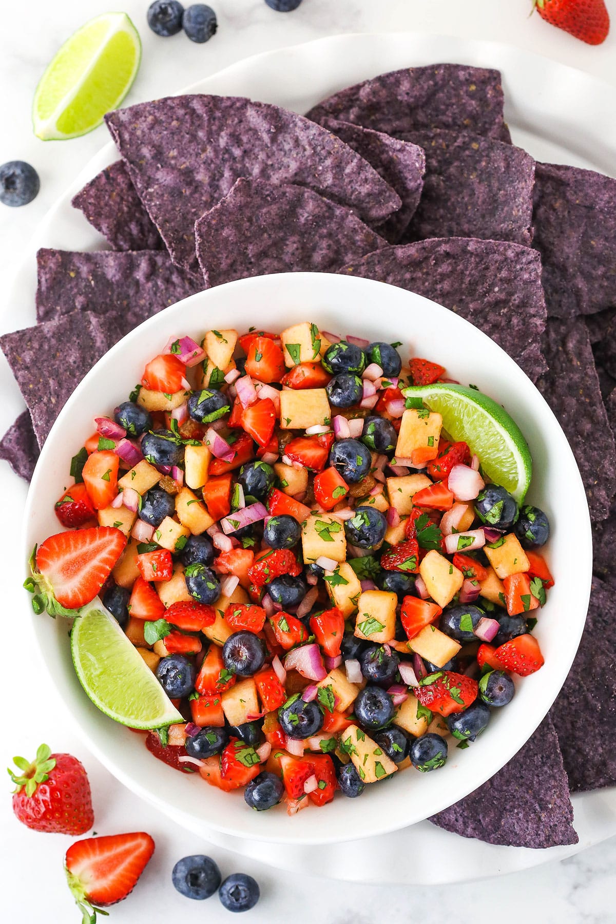 overhead image of berry fruit salsa in white bowl with blue tortilla chips