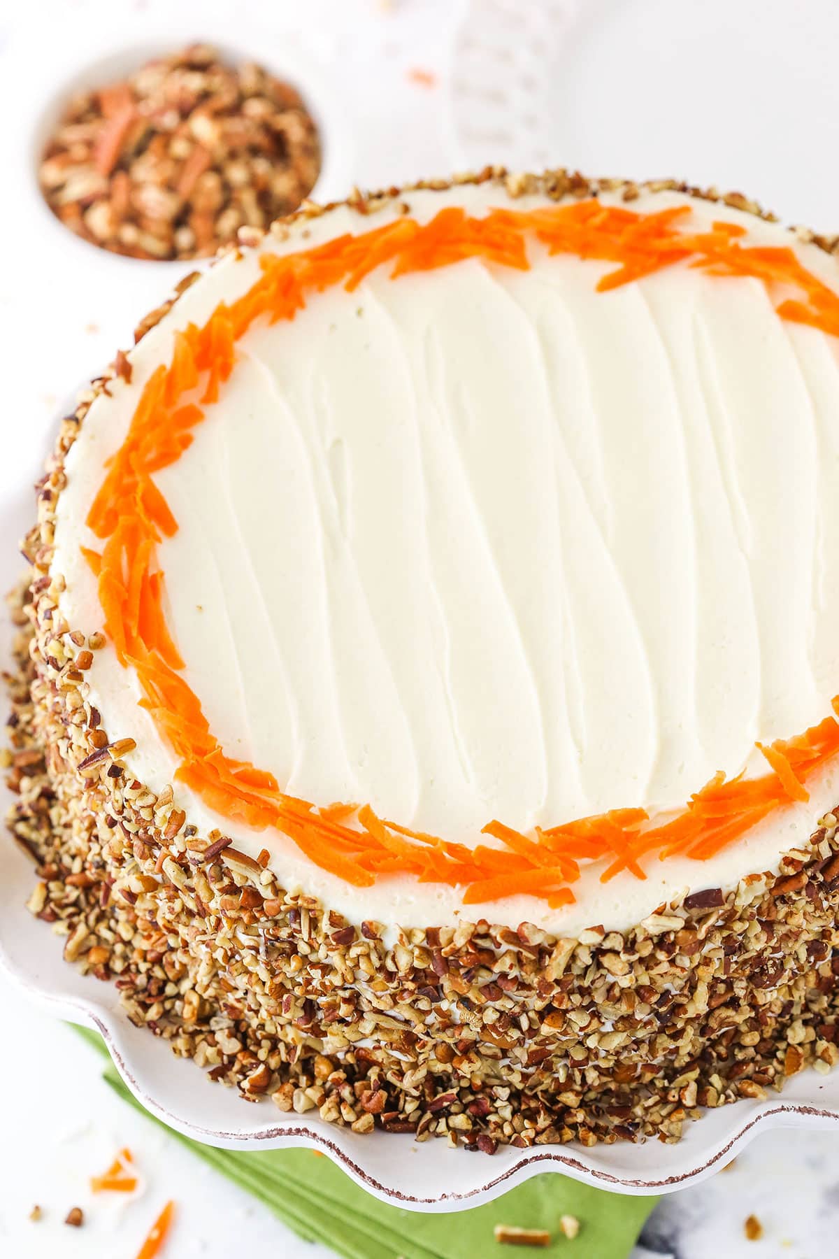 Overhead view of a full Cheesecake Swirl Carrot Cake on a white cake stand