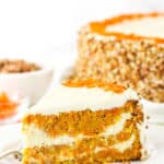 A slice of Cheesecake Swirl Carrot Cake on a white plate with a fork