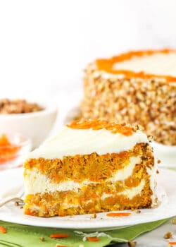A slice of Cheesecake Swirl Carrot Cake on a white plate with a fork