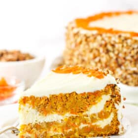A slice of Cheesecake Swirl Carrot Cake on a white plate with a fork