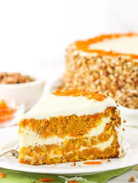 A slice of Cheesecake Swirl Carrot Cake on a white plate with a fork