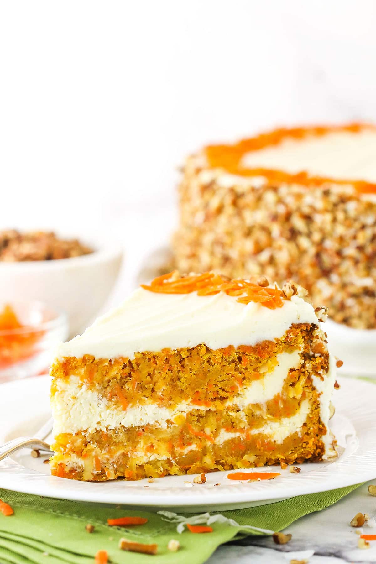 A slice of Cheesecake Swirl Carrot Cake on a white plate with a fork
