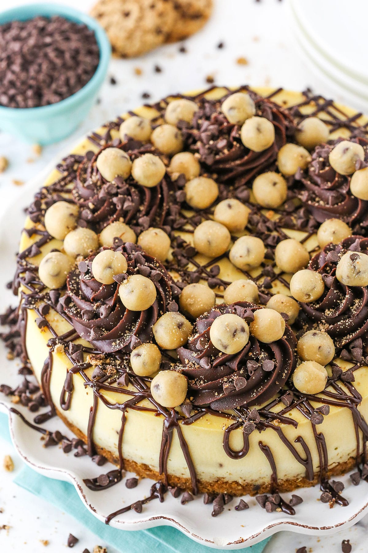 This Chocolate Chip Cookie Dough Cheesecake is made with a chocolate chip cookie crust and brown sugar cheesecake filled with chocolate chips and cookie dough! It's topped with chocolate ganache and more cookie dough for the ultimate treat! overhead image of cookie dough cheesecake with chocolate drizzle