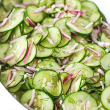 Homemade cucumber onion salad with dill and vinegar in a bowl.